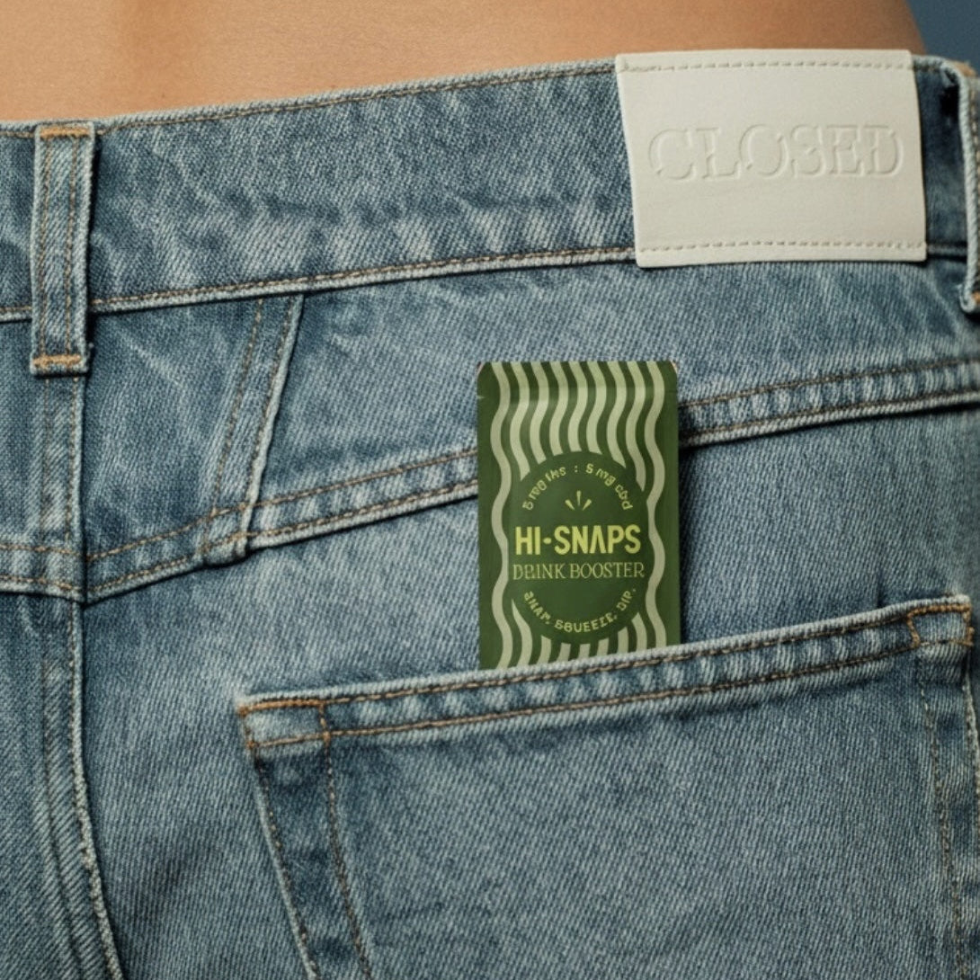 Close-up of a denim pocket with a green  unflavored HI-SNAPS drink booster packet.